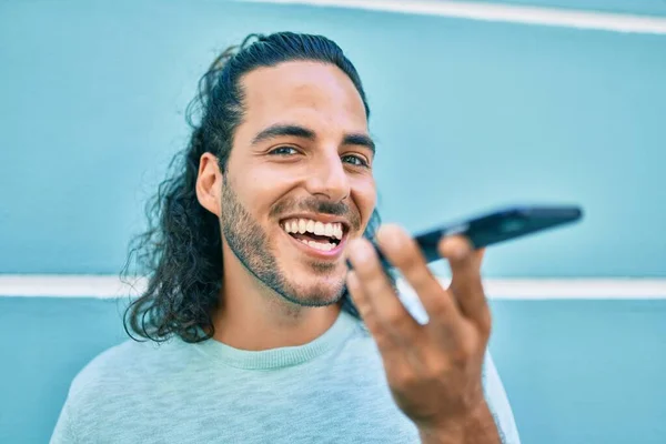 Joven Hombre Hispano Sonriendo Feliz Hablando Smartphone Apoyado Pared —  Fotos de Stock