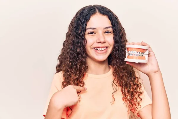 Hermosa Niña Con Cabello Rizado Sosteniendo Ortodoncia Señalando Dedo Uno — Foto de Stock