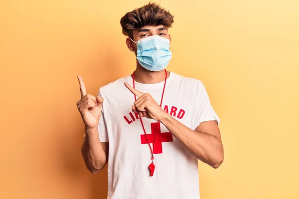 Joven Hispano Vistiendo Camiseta Salvavidas Usando Máscara Médica Sonriendo Mirando —  Fotos de Stock