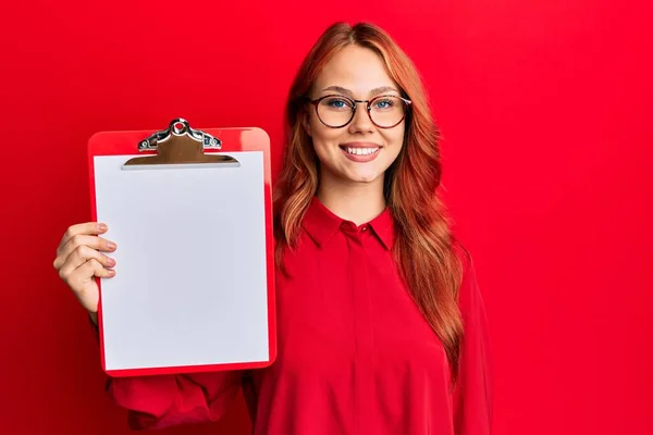 Young Redhead Woman Holding Clipboard Blank Space Looking Positive Happy — Stock Photo, Image