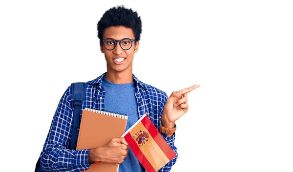 Joven Hombre Afroamericano Vistiendo Mochila Estudiante Sosteniendo Bandera Española Sonriendo —  Fotos de Stock