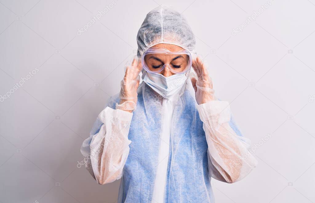 Middle age nurse woman wearing protection coronavirus equipment over white background with hand on head for pain in head because stress. Suffering migraine.