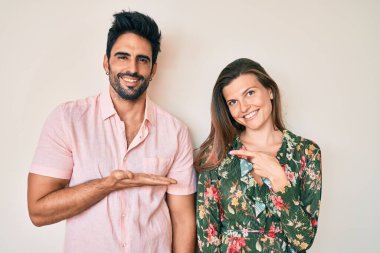 Genç ve güzel sevgili çifti kameraya hayret ve gülümseme içinde el ve parmak göstererek. 