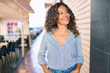 Orta yaşlı İspanyol kadın gülümseyerek şehirde mutlu mesut yürüyor..