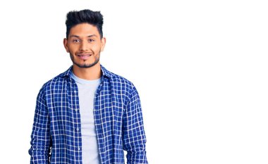 Yakışıklı Latin Amerikalı genç adam gündelik tişört giyiyor. Pozitif ve mutlu görünüyor. Kendine güvenen bir gülümsemeyle dişlerini gösteriyor. 