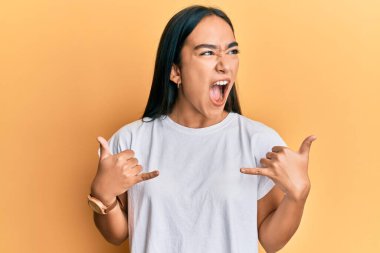 Genç Asyalı kadın elleriyle shaka işareti yapıyor. Kızgın ve kızgın çığlıklar atıyor. Öfkeyle bağırıyor. öfke ve agresif konsept. 
