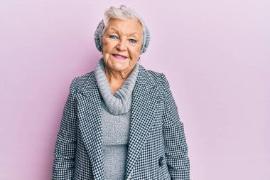 Yaşlı, gri saçlı, yünlü, kış süveteri giyen, yüzünde mutlu ve havalı bir gülümseme olan kadın. şanslı kişi. 