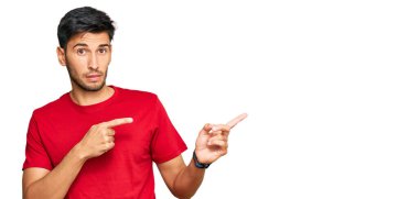 Gündelik kırmızı tişört giyen genç yakışıklı bir yana endişeli ve gergin, endişeli ve şaşırmış bir ifade takınıyor. 