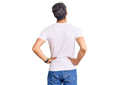 Sıradan beyaz tişörtler giyen genç, yakışıklı bir adam kolları vücudunda geriye doğru bakıyor. 