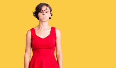 Kısa saçlı, sıradan giyinen, kolsuz tişörtlü, komik yüzlü güzel bir genç kadın. Havayla şişmiş ağız, çılgın bir ifade.. 