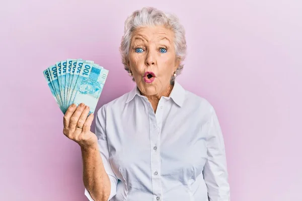 Starší Šedovlasá Žena Držící 100 Brazilských Pravých Bankovek Vystrašená Užaslá — Stock fotografie