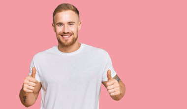 Genç İrlandalı sıradan kıyafetler giyen, başarı işareti takan, elinde olumlu bir jest yapan, gülümseyen ve mutlu bir adam. Neşeli ifade ve kazanan jest. 