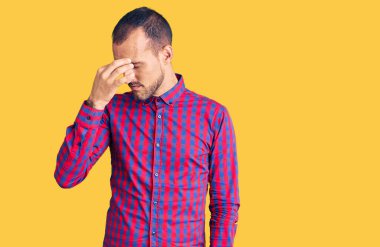 Gündelik kıyafetler giyen genç yakışıklı adam yorgun burnu ve gözleri ovuşturup yorgun ve baş ağrısı çekiyor. Stres ve hüsran kavramı. 