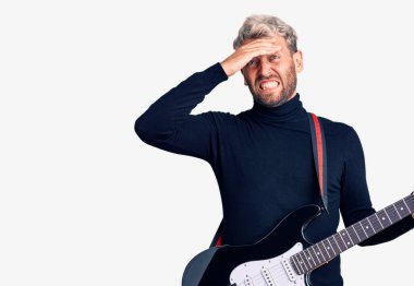 Genç, sarışın, elektro gitar çalan yakışıklı adam gergin ve sinirli, kafası karışık, şaşırmış ve sinirli. 