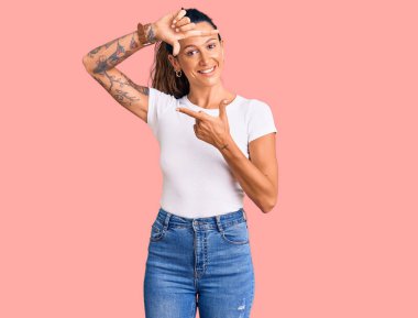 Gündelik beyaz tişört giyen, elleri ve parmakları gülen yüzlü, çerçeveli İspanyol bir kadın. yaratıcılık ve fotoğrafçılık kavramı. 