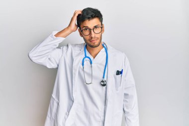 Doktor üniforması ve steteskop giyen genç yakışıklı adam soru sormayı merak ediyor. Şüpheyle kararsız, kafa kafaya düşünerek. Düşünceli kavram. 