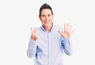 Kısa saçlı, iş kıyafetleri giyen genç bir kadın yedi numaralı parmaklarıyla gülümseyerek mutlu ve kendinden emin bir şekilde onu işaret ediyor.. 