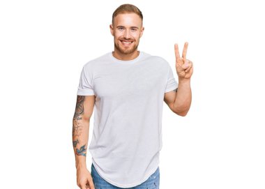 Genç İrlandalı sıradan kıyafetler giymiş iki numarayı gösterip işaret ederken kendinden emin ve mutlu bir şekilde gülümsüyor.. 