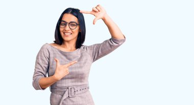 Gündelik kıyafetler giyen, gülümseyen, elleri ve parmakları mutlu yüzlü genç, güzel Latin bir kadın. yaratıcılık ve fotoğrafçılık kavramı. 