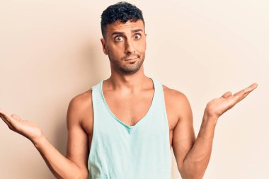 Gündelik kıyafetler giyen genç İspanyol adam habersiz ve kolları açık, hiçbir fikri ve şüpheli bir yüzü var.. 