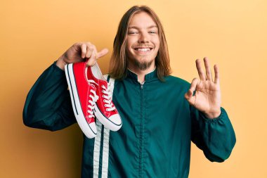 Uzun saçlı, kırmızı ayakkabılı, yakışıklı beyaz adam. Parmaklarıyla imza atıyor, gülümsüyor. Mükemmel bir sembol. 