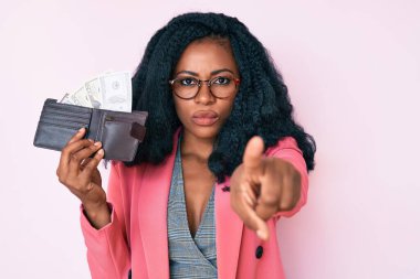 Cüzdanı elinde tutan güzel Afrikalı bir kadın kamerayı işaret eden dolarlarla sana ve kendine güvenen bir jest ciddi görünüyor. 