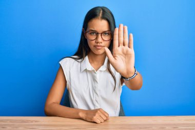 Gündelik giysiler giymiş güzel İspanyol kadın masada oturmuş avuç içiyle şarkı söylemeyi kesiyor. Yüzünde olumsuz ve ciddi bir jest olan uyarı ifadesi. 
