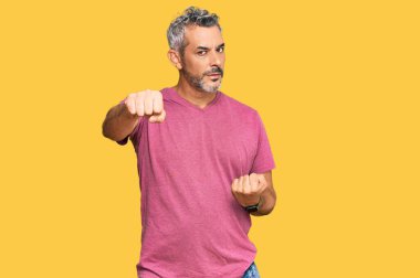 Orta yaşlı, gri saçlı, günlük kıyafetler giymiş dövüşmek için yumruk sallayan saldırgan ve öfkeli saldırı, tehdit ve şiddet uygulayan bir adam. 