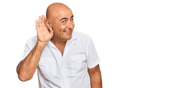 Bıyıklı, sıradan beyaz tişörtlü, ağzı kulaklarında, dedikoduları ve dedikoduları dinleyen olgun bir Orta Doğulu. Sağırlık kavramı. 