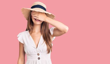 Yazlık elbise giyen, şapkalı, gülümseyen ve gülümseyen genç, güzel sarışın kadın şaşırmak için gözlerini kapatıyor. kör kavram. 