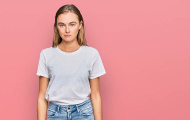 Sıradan beyaz tişört giyen güzel sarışın kadın yüzünde ciddi bir ifadeyle rahatlamış. Basit ve doğal bir şekilde kameraya bakıyorsun.. 