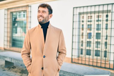 Zarif ceket giyen yakışıklı iş adamı dışarıda mutlu bir şekilde gülümsüyor.