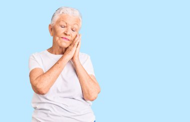 Son sınıf güzeli, mavi gözlü, gri saçlı, sıradan beyaz tişörtlü, uykulu, yorgun ve ellerinle poz verirken kapalı gözlerle gülümseyen bir kadın.. 