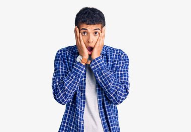 Genç afro-amerikan adam günlük giysiler giyiyor korkmuş ve şok olmuş, şaşırmış ve şaşırmış bir halde. 