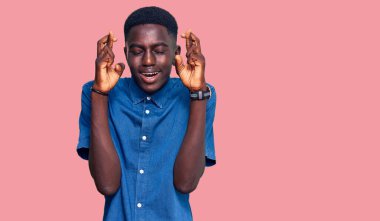 Genç Afro-Amerikalı sıradan kıyafetler giyen, umut ve gözlerin kapalı bir şekilde gülümseyerek el işareti yapan genç bir adam. Şans ve batıl inançlar. 