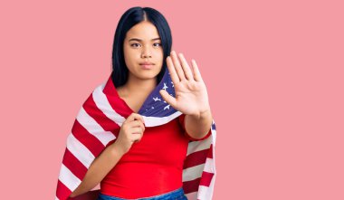 Amerika Birleşik Devletleri bayrağını elinde tutan güzel Asyalı kız dur işareti yapıyor ciddi ve kendinden emin bir ifadeyle, savunma hareketi yapıyor. 