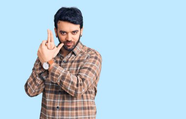 Latin asıllı genç adam gündelik giysiler giyiyor. Elinde sembolik bir silah var. El hareketleriyle cinayet silahlarıyla oynuyor. 