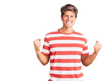 Gündelik kıyafetler giyen, mutlu ve heyecanlı genç bir adam kollarını kaldırmış, gülümseyen ve başarı için çığlık atan kazanan bir jest yapıyor. kutlama konsepti. 