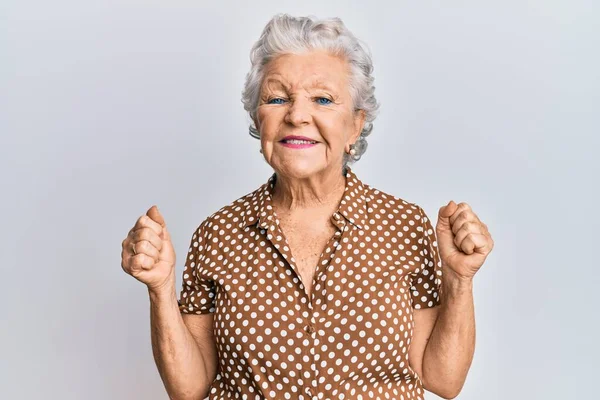 身穿休闲装的白发苍苍的老年妇女对举手表决和睁开眼睛的成功感到惊讶和惊奇 获奖者概念 — 图库照片