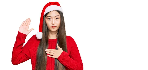 Jovem Chinesa Vestindo Chapéu Natal Jurando Com Mão Peito Palma — Fotografia de Stock