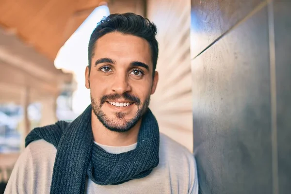 Joven Hombre Hispano Sonriendo Feliz Usando Bufanda Apoyada Pared Ciudad —  Fotos de Stock