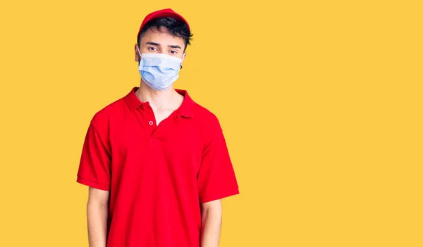 Fiatal Spanyol Férfi Kézbesítő Egyenruhában Orvosi Maszkban Komoly Arckifejezéssel Egyszerű — Stock Fotó