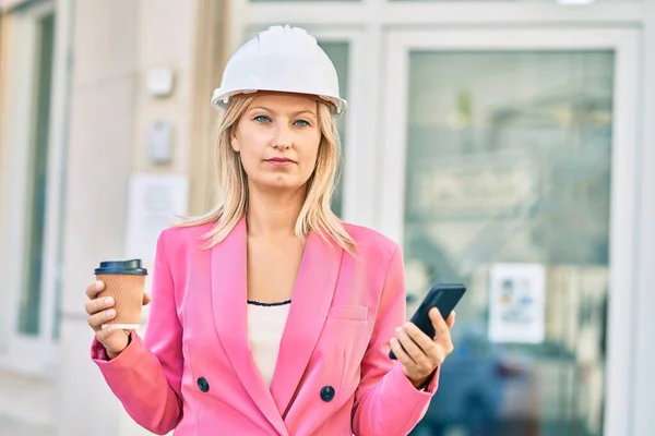 若い白人建築家の女性が市内でスマートフォンやコーヒーを使って — ストック写真