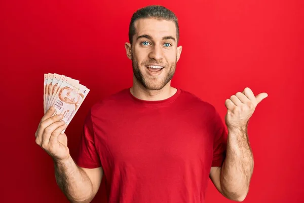 Young Caucasian Man Holding Singapore Dollars Banknotes Pointing Thumb Side — Stock Photo, Image