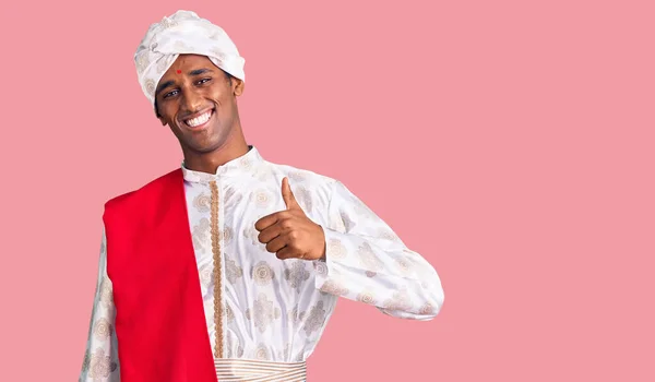 穿着传统雪旺尼酒的非洲帅哥看到穿着快乐大拇指的衣服举手表决 赞成的表情看着相机显示的成功 — 图库照片