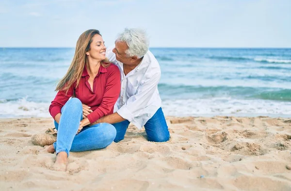 Pareja Hispana Mediana Edad Sonriendo Feliz Abrazándose Sentada Playa —  Fotos de Stock