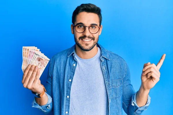 Joven Hispano Sosteniendo Billetes Lira Turca Sonriendo Feliz Señalando Con —  Fotos de Stock