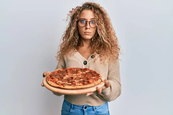 Beautiful Caucasian Teenager Girl Eating Tasty Pepperoni Pizza Skeptic Nervous — Stock Photo, Image