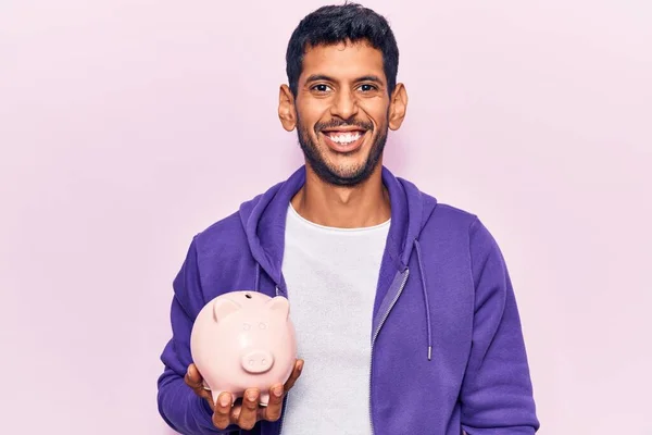 Jovem Latino Segurando Porquinho Banco Olhando Positivo Feliz Sorrindo Com — Fotografia de Stock