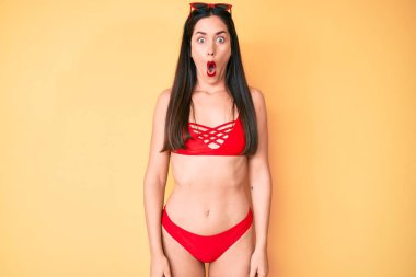 Genç, beyaz, güzel bir kadın bikini giyiyor. Korkmuş ve ağzı açık, şaşırmış ve şaşırmış. 
